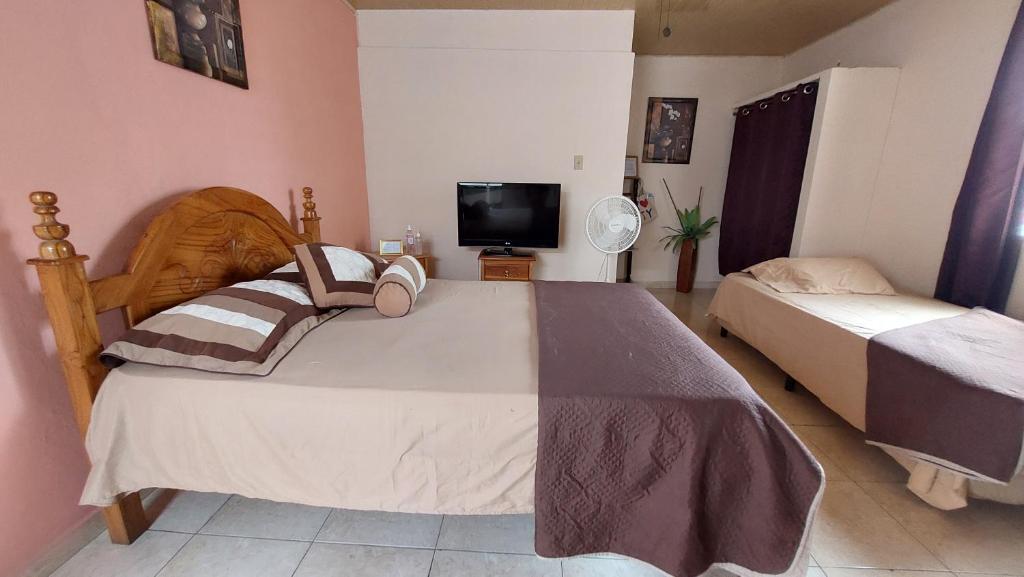 1 dormitorio con 2 camas y TV de pantalla plana en Tocumen Sweet Home, en Cabuya