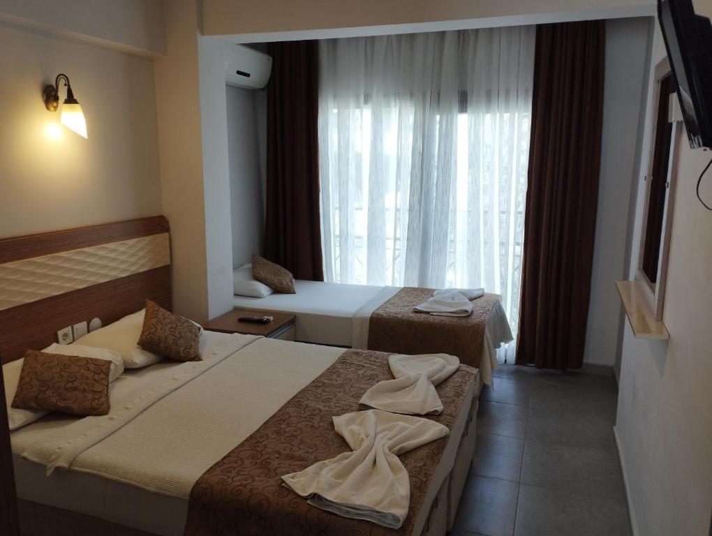 a hotel room with two beds and a window at Soleil Otel in Kuşadası