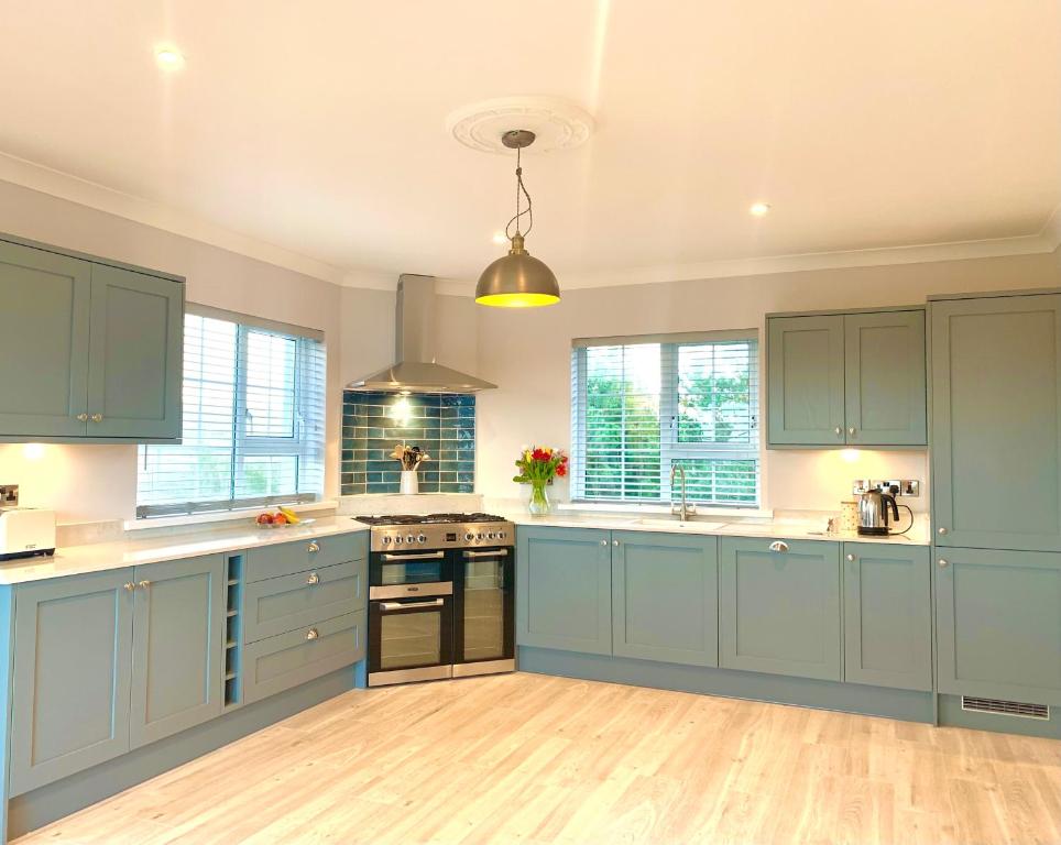 a large kitchen with blue cabinets and wooden floors at The Lake House Dungloe in Dungloe