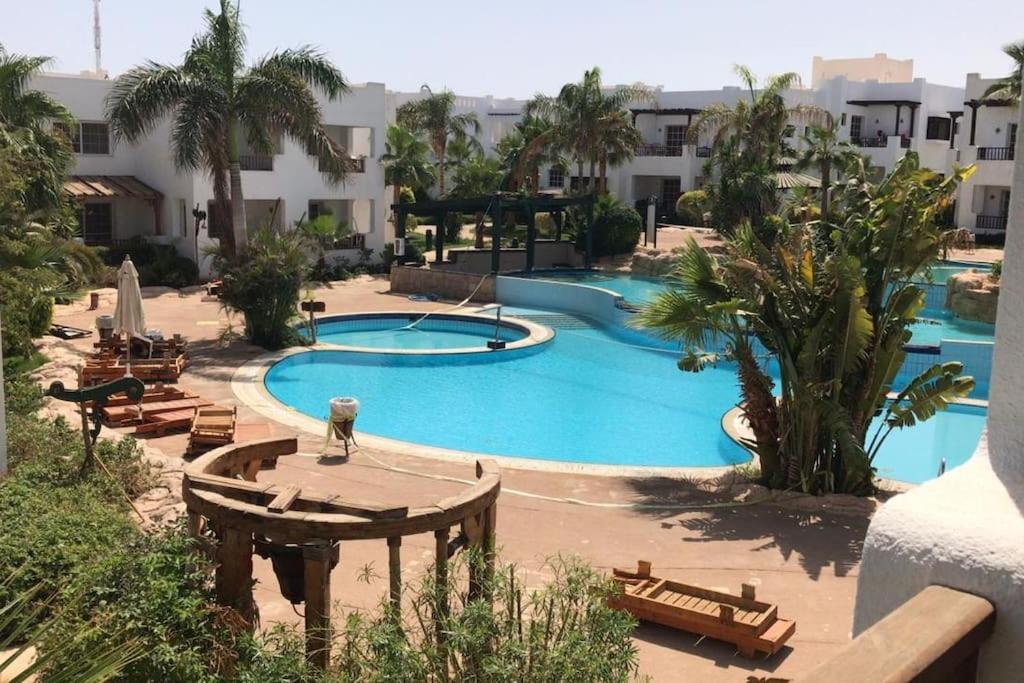 - une grande piscine avec des tables et des chaises dans un complexe dans l'établissement Delta best, à Charm el-Cheikh