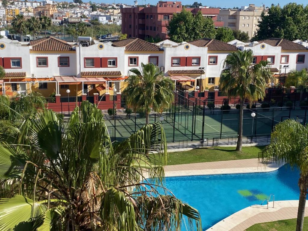 a view of a pool with palm trees and buildings at People Homes Bajo Guía in Sanlúcar de Barrameda