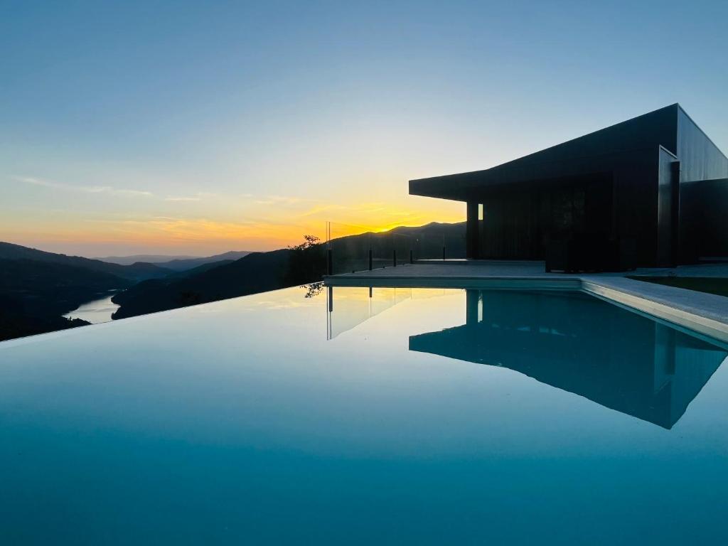 a house with a swimming pool with the sunset in the background at Encosta do Gerês Village in Ventosa