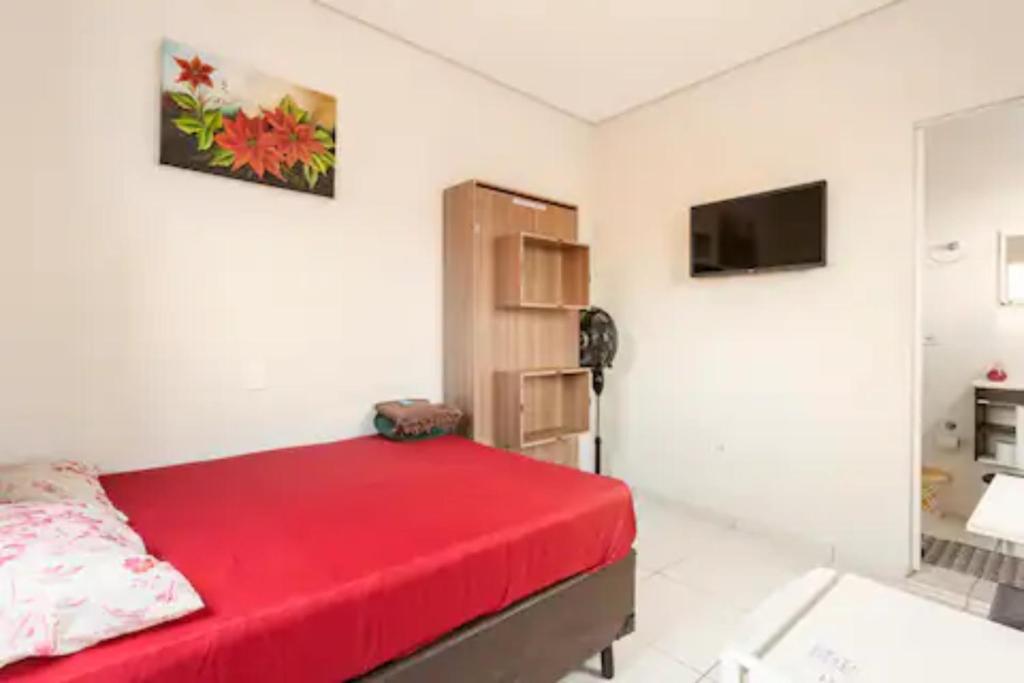 um quarto com uma cama vermelha e uma televisão em Pousada Casa da Fernanda, Suíte Sky na Praia Grande