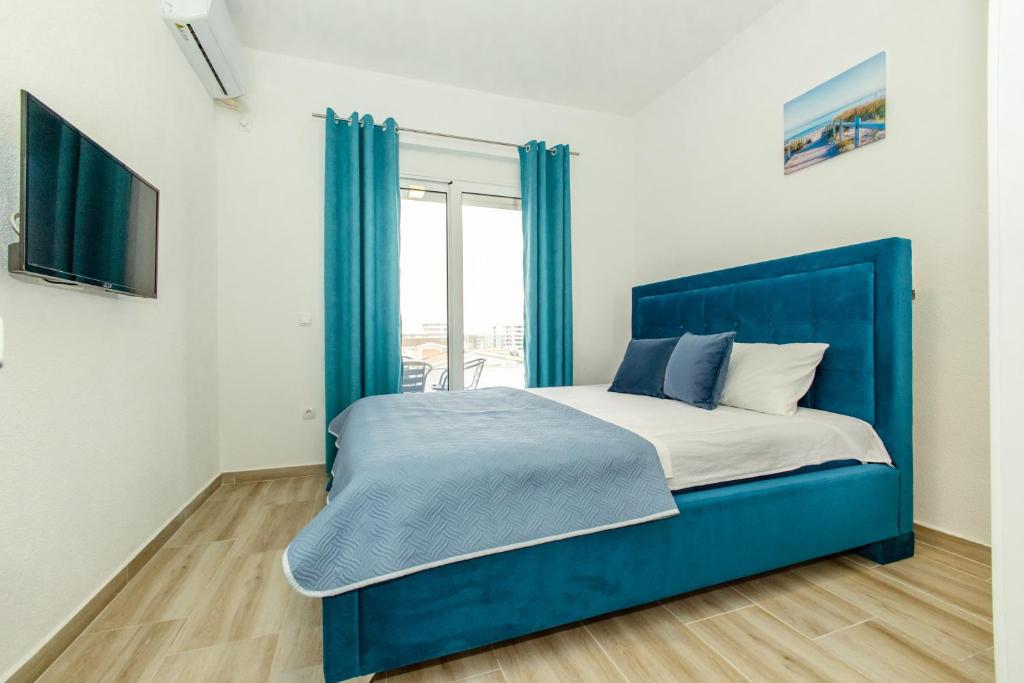 a blue bed in a room with a window at DERON Apartments in Ulcinj