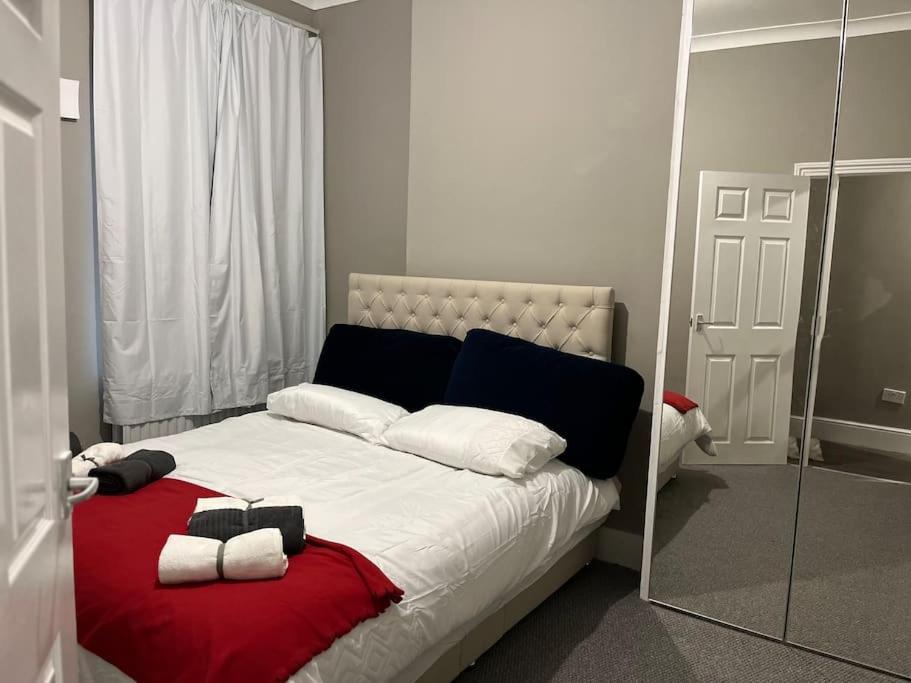 a bedroom with a bed with a red blanket and a mirror at A beautiful ground-floor flat. in London