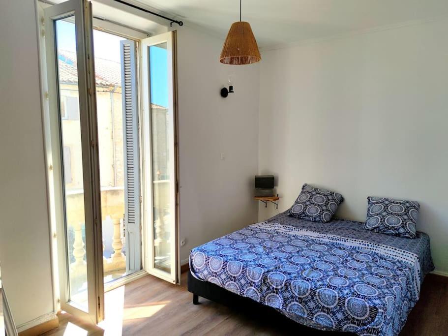 a bedroom with a bed and a large window at Appartement DeGaulle in Châteaurenard