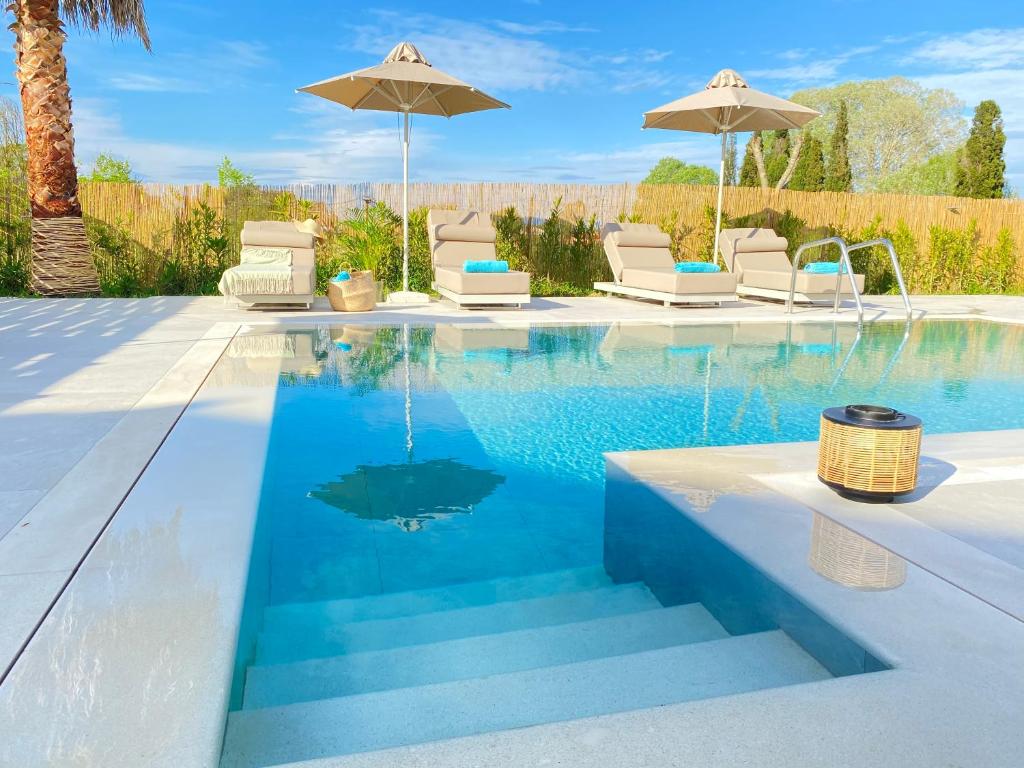 una piscina con sedie e ombrelloni in un cortile di My Corfu Luxury Villa with private pool at Sidari a Sidari
