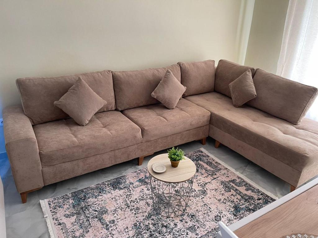 un divano marrone in un soggiorno con tavolo di ThePlaceForYou Central Apt a Shkodër
