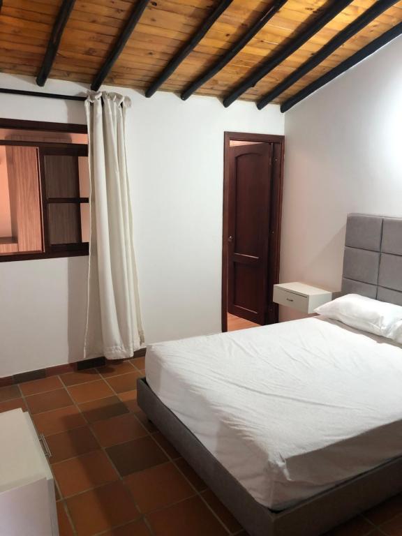 1 dormitorio con cama blanca y techo de madera en Cabaña VioletaZap, en Zapatoca