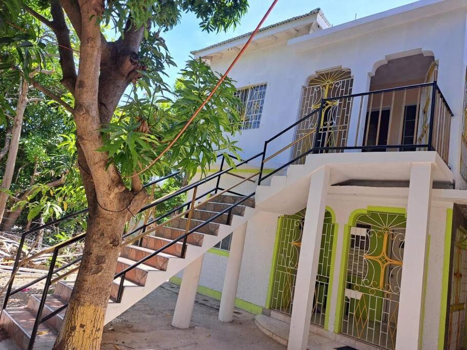 a white building with stairs next to a tree at Mango tree Oasis in Treasure Beach