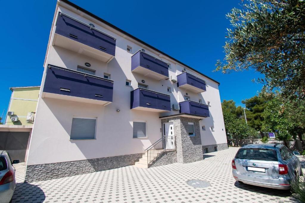 een gebouw met blauwe ramen en een auto voor de deur bij Apartment Lena in Vodice