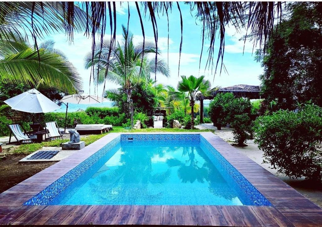 una piscina en un patio con mesa y sombrilla en El Mirador de Punta Veleros en Los Órganos