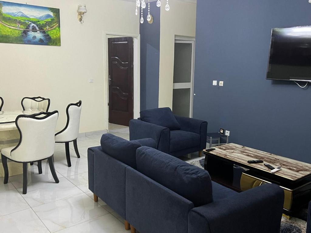 uma sala de estar com um sofá, uma mesa e uma televisão em Primeshare Luxury Apartments for Family Travelers with Swimming Pool, Yaounde em Iaundé