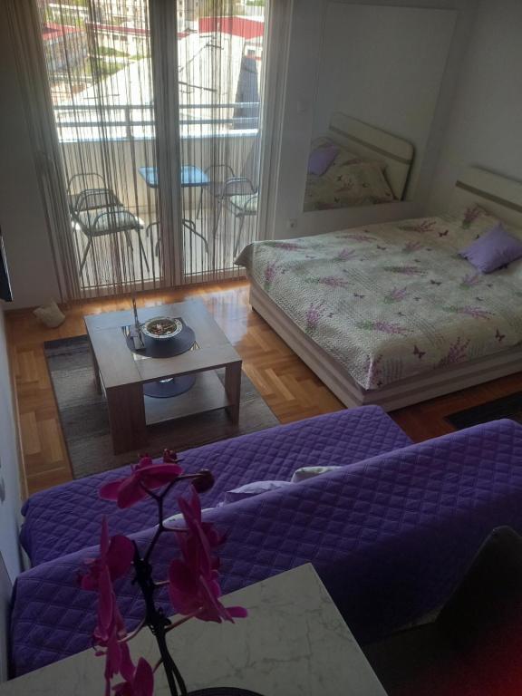 una habitación con 2 camas y una mesa con flores en Apartman Magdalena, en Trebinje