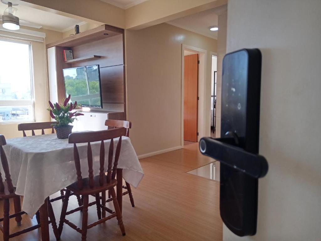a dining room with a table and a tv on a wall at AP Moderno in Pelotas