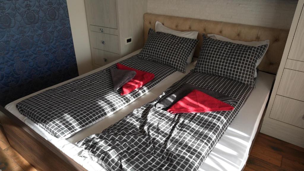 dwa łóżka z czarno-białą pościelą i czerwonymi poduszkami w obiekcie Bella studios w mieście Kruševac