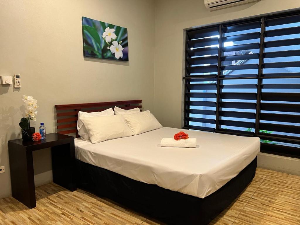 a bedroom with a bed with a flower on it at Garden Apartments in Nadi