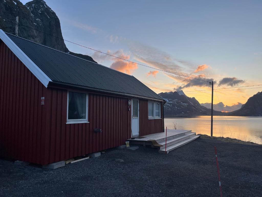 un edificio rosso con un molo accanto a un corpo idrico di Reinefjord panorama a Moskenes