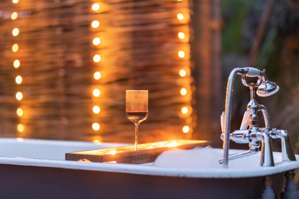 a bath tub with a glass of wine in it at Luxury Glamping Cabin with Outdoor Bath on Cornish Flower Farm in Truro