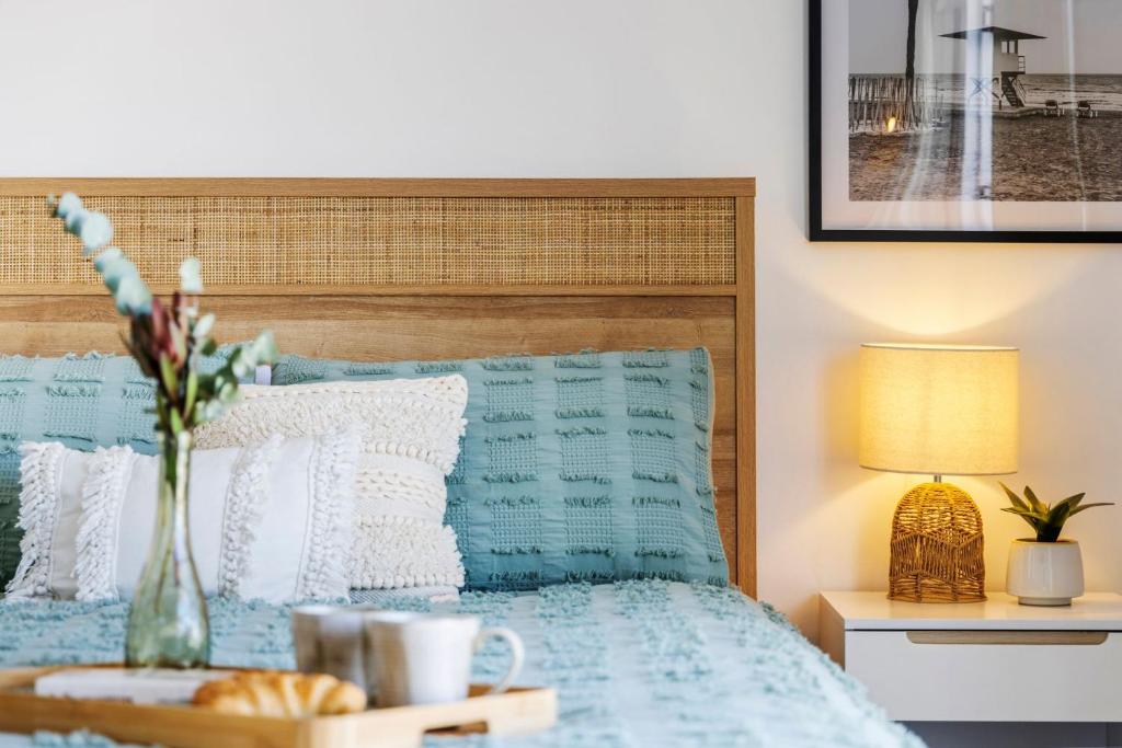a bedroom with a bed and a table with a vase of flowers at Sandcastles at the Beach - Linen Supplied & Beds Ready on Arrival in Fingal Bay