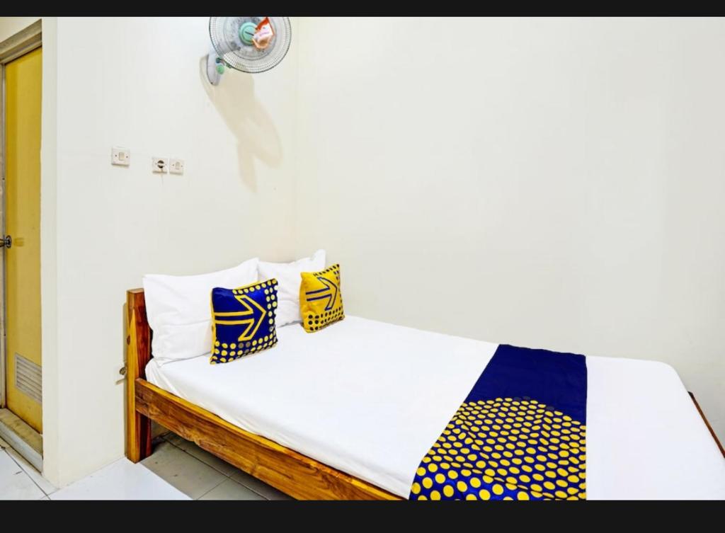 a bed with yellow and blue pillows on it at guest house RUMAH KALOKA in Triwung