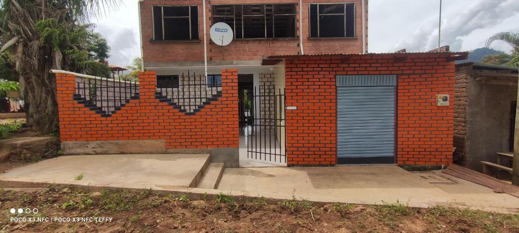 a brick building with a gate in front of it at Suites Hostal V&D Caranavi, La Paz in Caranavi