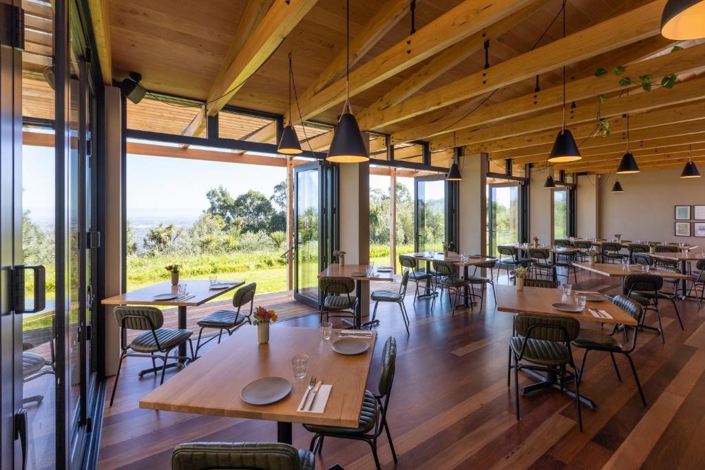 restauracja ze stołami i krzesłami oraz dużymi oknami w obiekcie Tussock Hill Vineyard Retreats w mieście Christchurch