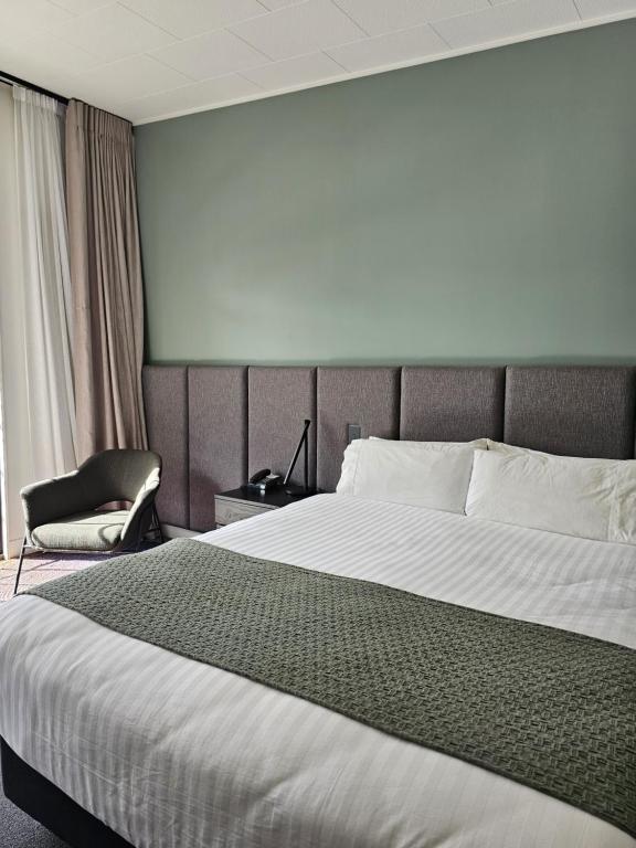 a hotel room with a large bed and a chair at The Avenue in Whanganui