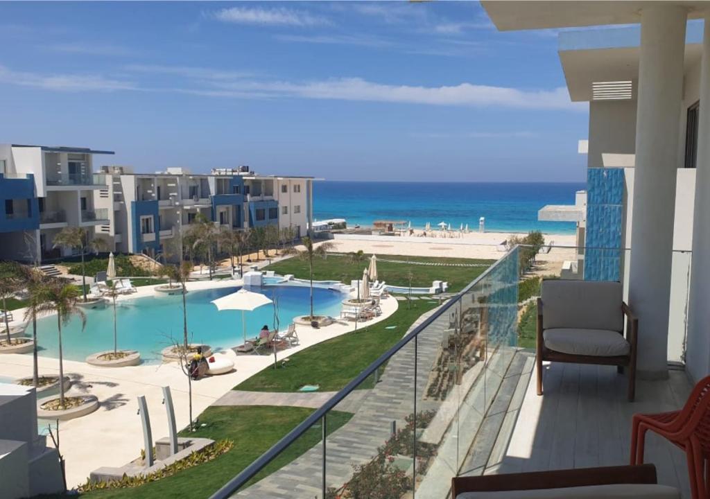 a balcony with a view of a pool and the beach at Modern Style Serviced Apartment at Fouka Bay North Coast with Pool and Sea View in Marsa Matruh