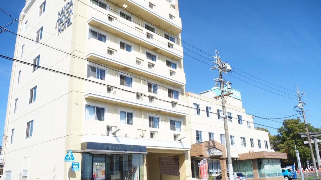 a tall white building on the corner of a street at Handa Station Hotel in Handa
