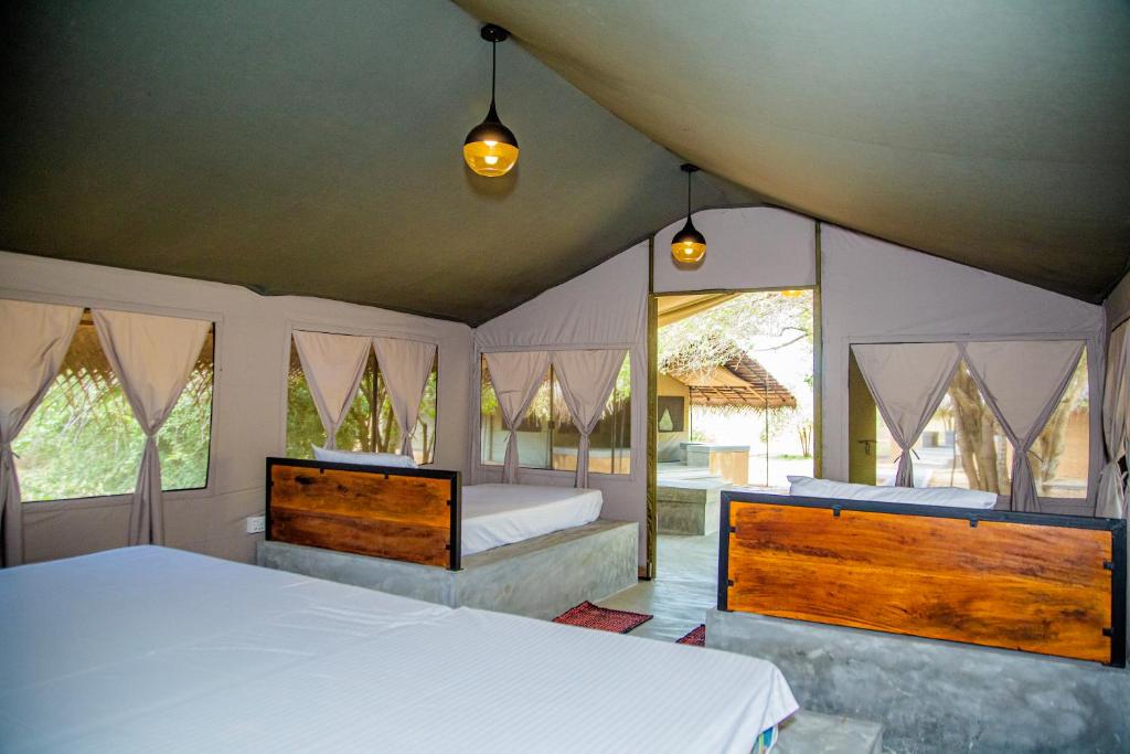 a bedroom with two beds and two windows at Yala Wild Hut - Yala in Tissamaharama