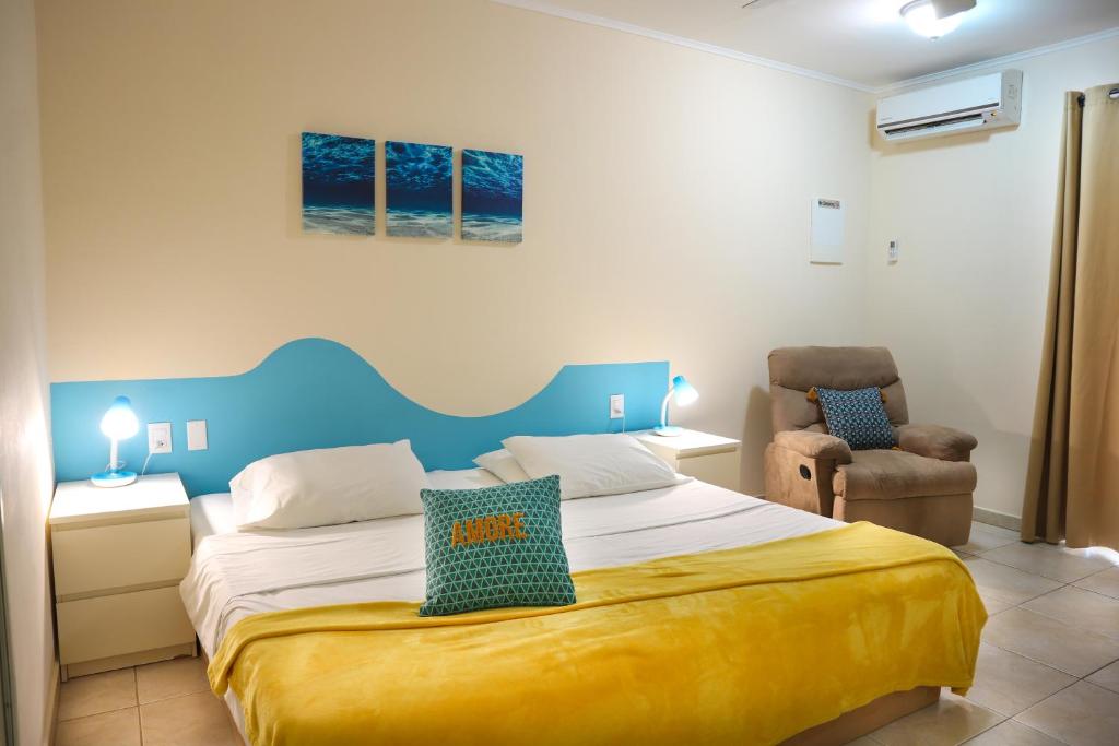 een slaapkamer met een groot bed en een stoel bij Aqua Viva Suites in Kralendijk
