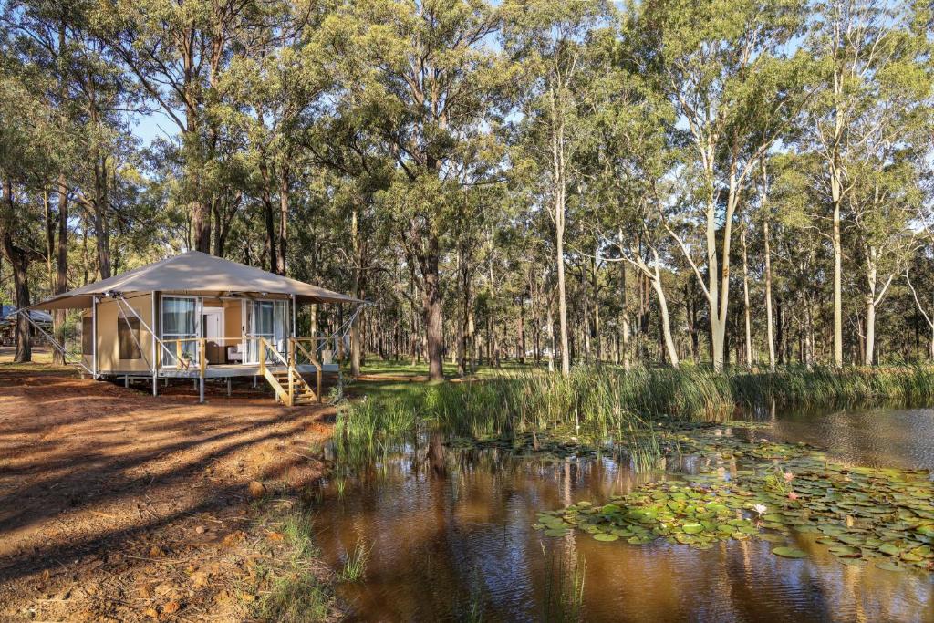 a gazebo next to a river with trees at Two Fat Blokes Outback Adventure Glamping in Pokolbin