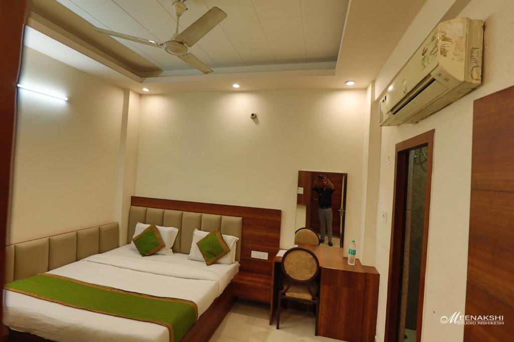 a bedroom with a bed and a desk with a mirror at Hotel Haridev in Roorkee