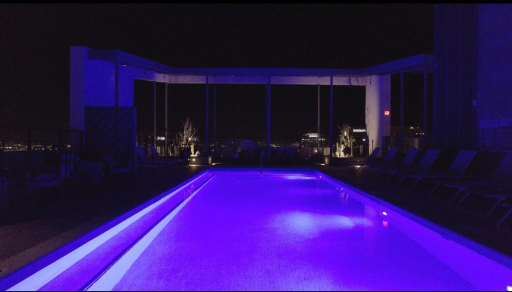 a swimming pool lit up at night with purple lights at Highrise the Heart of Downtown in Phoenix