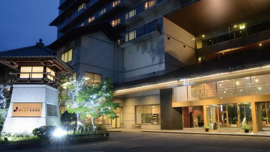 un grand bâtiment avec un arbre en face dans l'établissement Yutorelo Nasushiobara, à Nasushiobara