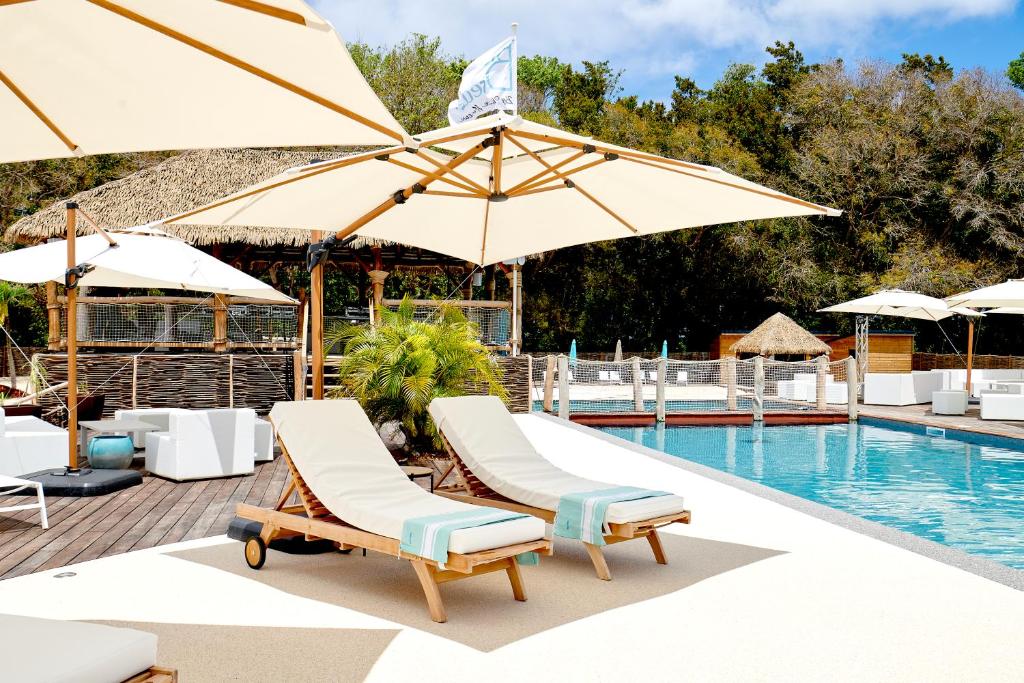 a pool with lounge chairs and umbrellas next to a swimming pool at Blue Dream Paradise - Résidence plage & piscine in Grand-Bourg