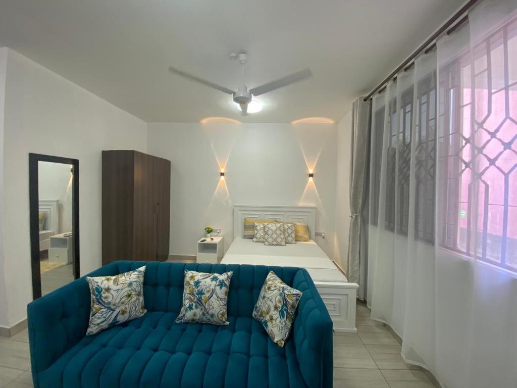 a living room with a blue couch in front of a bed at Love-tribe studio apartment in Mombasa