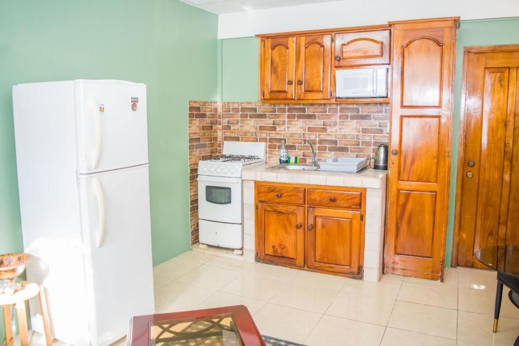 eine Küche mit Holzschränken und einem weißen Kühlschrank in der Unterkunft Ebenezer's Haven in Roseau