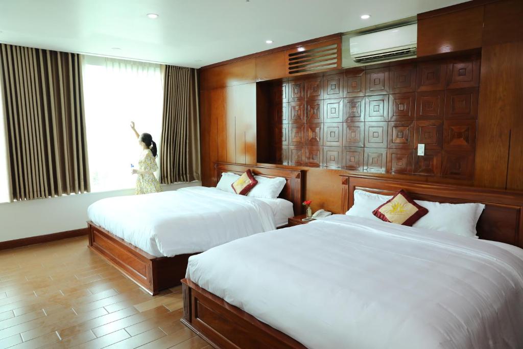 a hotel room with two beds and a window at Thành Vinh Hotel in Ho Chi Minh City
