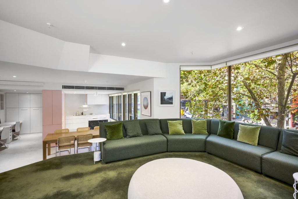 a living room with a green couch and a kitchen at Bourke Street Urban Retreat in Melbourne