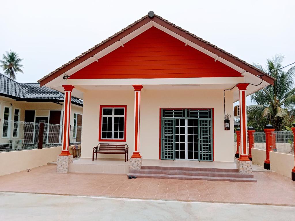 una pequeña casa con techo rojo en Adilah Homestay B en Pasir Puteh