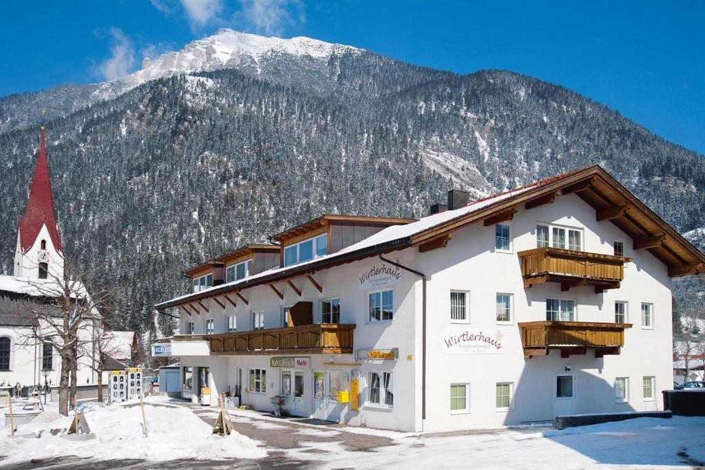 a large white building with a mountain in the background at Apartment in Bichlbach at the lake in Bichlbach