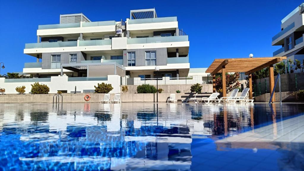 un edificio con piscina frente a un edificio en Amplio y cómodo apartamento., en Granadilla de Abona