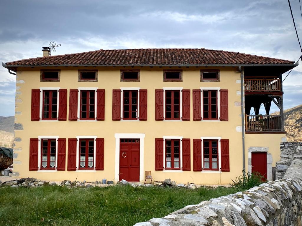 a yellow house with red windows and a fence at À l'orée du Cagire in Juzet-dʼIzaut