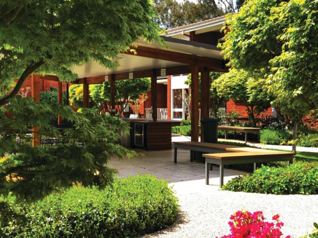 a pavilion with a picnic table and benches in a garden at Forrest Hotel & Apartments in Canberra