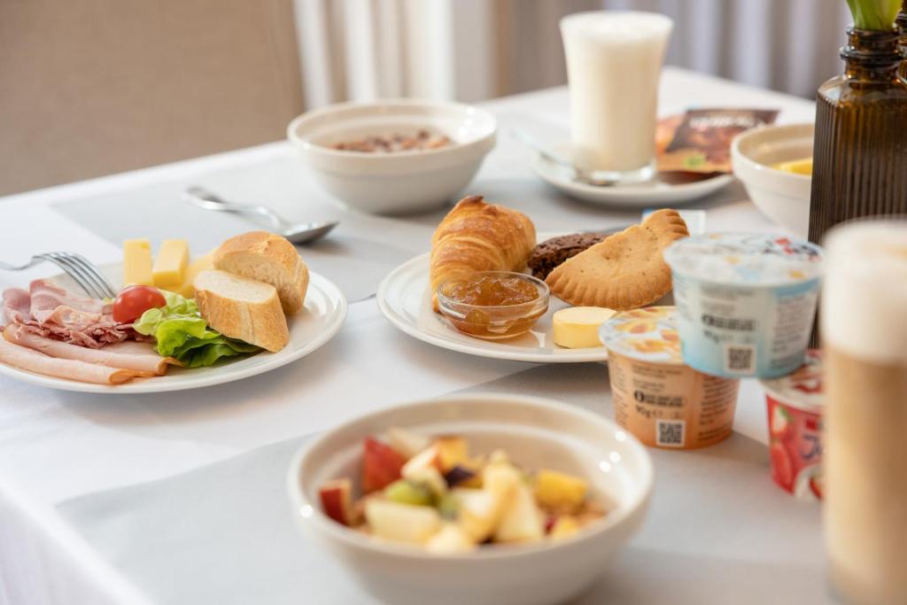 a white table with plates of food on it at Adhhoc Hotel in Naters