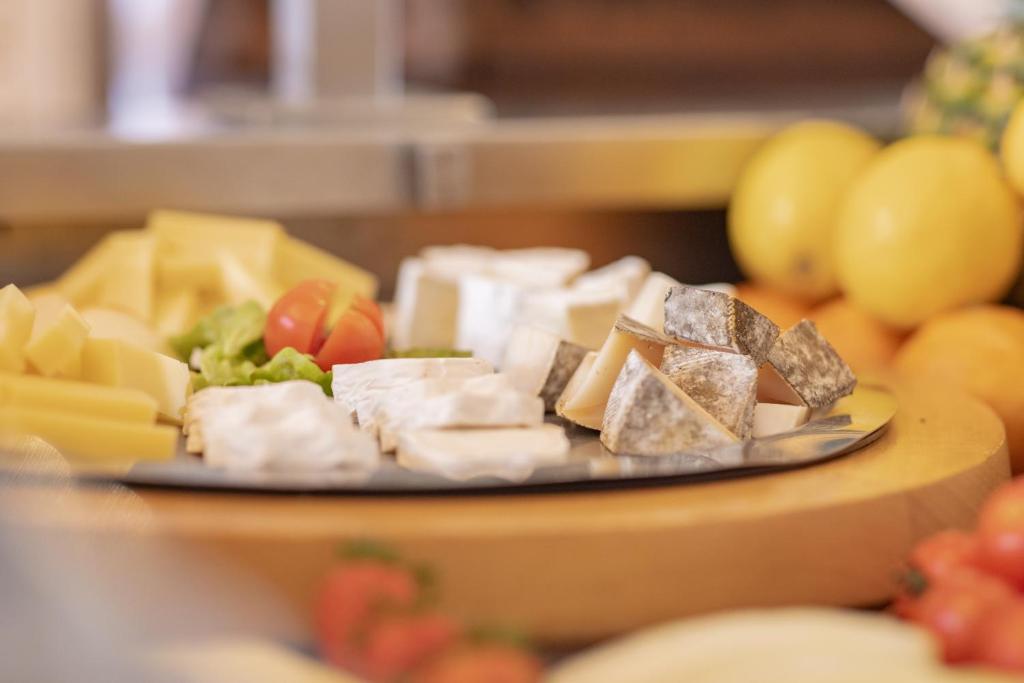 a plate of cheese and fruit on a table at Adhhoc Hotel in Naters