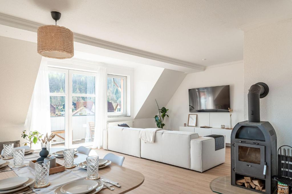 ein Wohnzimmer mit einer weißen Couch und einem Kamin in der Unterkunft Premium Apartment - Ausblick - Kamin - Balkon - Smart TV - Kaffeevollautomat in Wernigerode