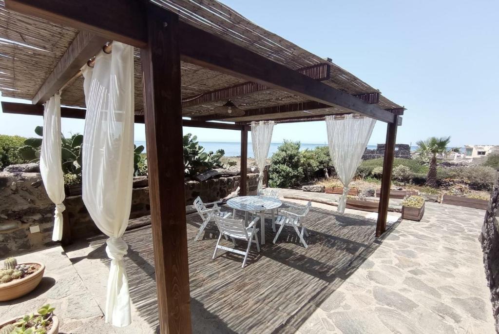 patio con tavolo e sedie sotto un pergolato di Pantelleria 4 passi dal mare a Pantelleria